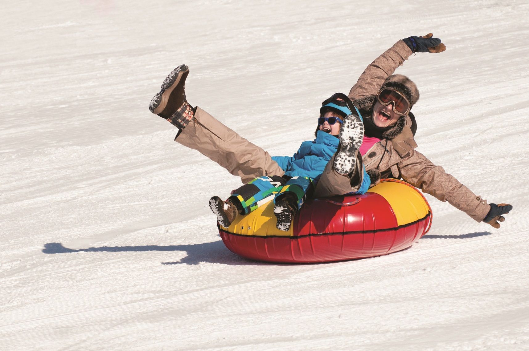 Young woman and little boy having fun in snow tube